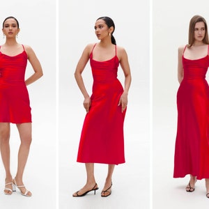 Puede incluir: Tres mujeres con vestidos de sat&eacute;n rojo de diferentes longitudes. Los vestidos tienen un cuello de pico y tirantes finos. Las mujeres est&aacute;n de pie sobre un fondo blanco.
