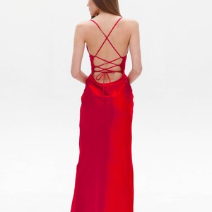 Puede incluir: Un vestido maxi de sat&eacute;n rojo con la espalda atada en forma de cruz.