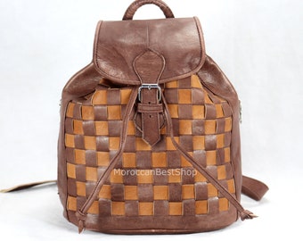 May include: A brown leather backpack with a woven checkered pattern. The backpack has a buckle closure and a drawstring top.