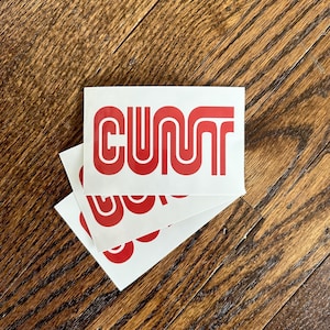 May include: Three white stickers with the word "CUNT" printed in red, stacked on top of each other.
