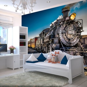 May include: A white daybed with blue and white pillows in front of a wall mural featuring a vintage steam locomotive with the number 484 on the side. The train is emitting smoke and has a bright yellow headlight.