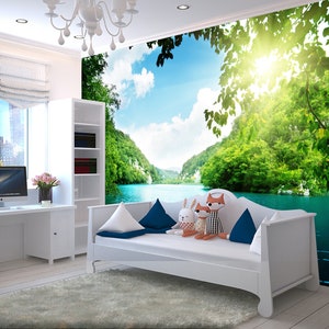 May include: A white daybed with blue and white cushions in front of a wall mural depicting a lush green forest and a blue lake. The sun shines brightly in the sky.