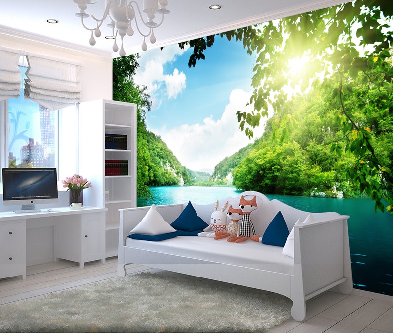 May include: A white daybed with blue and white cushions in front of a wall mural depicting a lush green forest and a blue lake. The sun shines brightly in the sky.