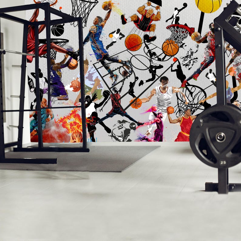 A gym interior with a wall mural featuring a basketball theme. The mural is a collage of basketball players in various poses, basketballs, and basketball hoops. The gym also has a weight bench, dumbbells, a kettlebell, and a blue exercise ball.
