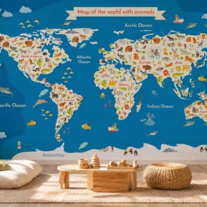 Puede incluir: Un gran mural de mapa del mundo azul con ilustraciones de animales, océanos etiquetados y el texto "Map of the world with animals". El mapa está en una habitación infantil con muebles de madera y un cojín de suelo.