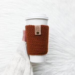 May include: A white ceramic mug with a colourful floral design. The mug has a handle and a wide opening. The flowers are in shades of pink, purple, and yellow. The mug is likely for hot drinks.