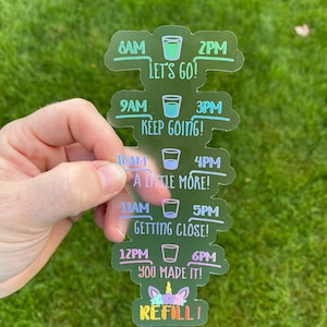 May include: A clear sticker with a unicorn graphic and the text "REFILL!"  The sticker is divided into sections with times from 8 AM to 6 PM and the text "LET'S GO!" "KEEP GOING!" "A LITTLE MORE!" "GETTING CLOSE!" and "YOU MADE IT!"