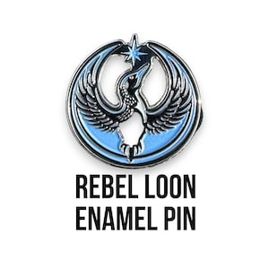 May include: Enamel pin featuring a stylized bird design in shades of blue, black, and silver. The pin has a circular shape with the words "REBEL LOON ENAMEL PIN" in bold black letters below the pin.