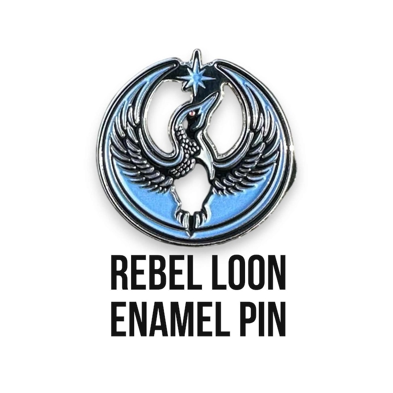 May include: Enamel pin featuring a stylized bird design in shades of blue, black, and silver. The pin has a circular shape with the words "REBEL LOON ENAMEL PIN" in bold black letters below the pin.