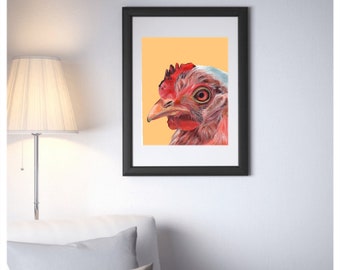 Puede incluir: Un retrato de cerca de una gallina roja y blanca con un fondo melocotón. La gallina está mirando hacia la izquierda del marco. La imagen está en un marco negro.