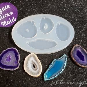 May include: A clear silicone mold for agate slices with the text "Agate Slices Mold". The mold is oval-shaped with four cavities. Several colorful agate slices in shades of purple, blue, and white are displayed next to the mold.