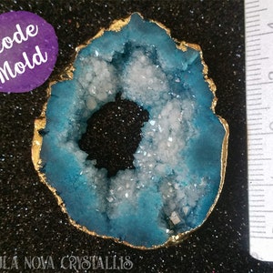 Puede incluir: Un molde de geoda azul y blanco con un borde dorado. El molde tiene un diámetro de aproximadamente 5 cm. El texto "Geode Mold" está escrito en morado sobre un círculo blanco.