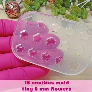 May include: A clear, rectangular mould with 15 flower-shaped cavities. The mould is held by a gloved hand. The text at the bottom reads "15 cavities mould tiny 8 mm flowers". The flowers are 8 mm in size.