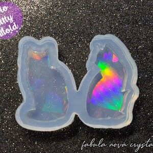 Puede incluir: Un molde de silicona transparente con dos formas de gato. El molde está diseñado para crear artesanías de resina holográfica. El texto "Holo Kitty Mold" es visible en la imagen.