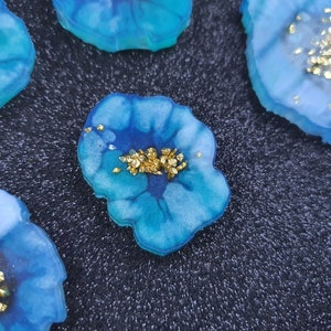May include: Four blue and white resin coasters with gold glitter accents. The coasters are shaped like agate slices and have a unique, organic look.