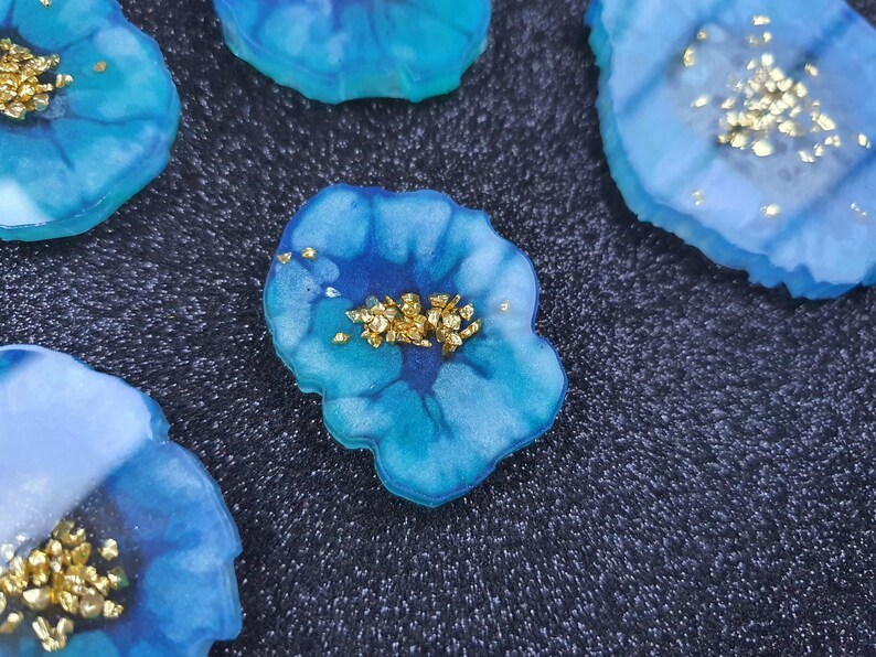 May include: Four blue and white resin coasters with gold glitter accents. The coasters are shaped like agate slices and have a unique, organic look.