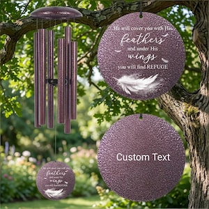 May include: A purple wind chime featuring a circular metal plate with the text 'He will cover you with His feathers and under His wings you will find REFUGE' and a white feather graphic, alongside a second circular plate with 'Custom Text'.