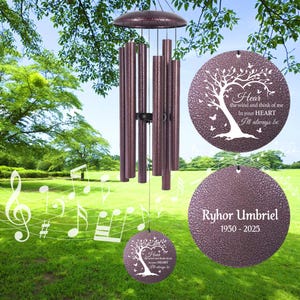 May include: A bronze-colored wind chime with cylindrical tubes and a circular top and bottom. The chime has two circular pendants with a tree design and the text "Hear the wind and think of me In your HEART I'll always be" and "Ryhor Umbriel 1950-2025".