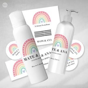 Puede incluir: Un conjunto de detalles de boda con temática de arcoíris. Los detalles incluyen una botella de loción para manos, una botella de laca para el cabello, un paquete de pinzas para el cabello y tres pegatinas redondas con un diseño de arcoíris. Las pegatinas tienen el texto "Mate & Ana" y "Nuestra Boda".