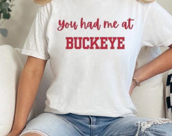 May include: White t-shirt with the text "You had me at Buckeye" in red lettering.