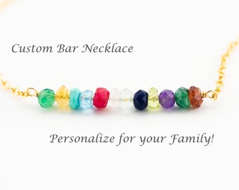 May include: A gold chain necklace with a bar pendant featuring a row of colorful gemstones. The gemstones include green, yellow, turquoise, red, white, navy, and purple. Text on the image reads "Custom Bar Necklace" and "Personalize for your Family!"