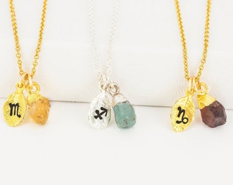 May include: Gold and silver necklaces with leaf pendants and raw gemstone accents. Each necklace features a different zodiac symbol: Scorpio, Sagittarius, and Capricorn. The gemstones are in shades of yellow, blue-green, and brown.