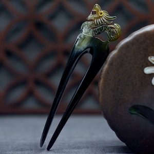 May include: A black and green hair comb with a dragon design. The dragon is carved into the comb and has a yellow eye.