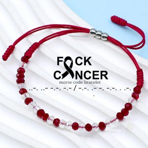 May include: Red and clear crystal beaded bracelet with a red string and silver beads. The bracelet has a red ribbon tied in a knot at the end. The bracelet has the text "F*CK CANCER" and "morse code bracelet" printed below it.