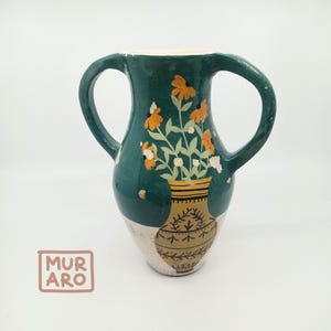 May include: A teal ceramic vase with two handles, painted with white and orange flowers and a smaller vase with a gold and brown pattern.