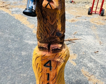 May include: A carved wooden bear holding a lantern, standing on a wooden post with the numbers 4161 carved into it.