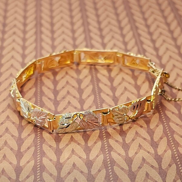 Circa 1985, a 7" long x 7mm wide 10k yellow gold tri-gold Black Hills Gold bracelet with safety clasp and safety chain.