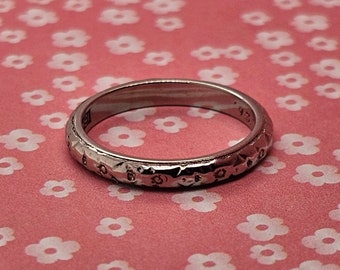 Circa 1926, a 2.6mm wide 18k white gold band with flower pattern, size 5.