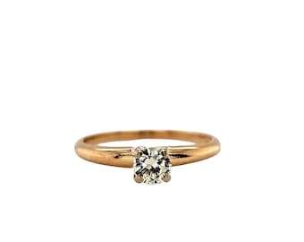 May include: A gold ring featuring a single, round, clear diamond. The band is polished, and the diamond is held in place by four prongs. The ring is a classic solitaire design, a timeless piece of jewellery.