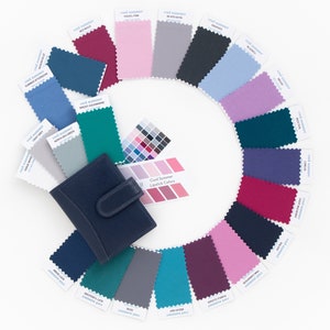 May include: A color palette guide for the Cool Summer color season. The guide includes 16 fabric swatches in various shades of blue, green, purple, pink, and gray. The swatches are arranged in a circle around a small card that reads "Cool Summer Lipstick Colors".