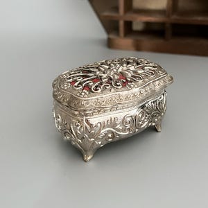 脚付きの小さな装飾ジュエリーボックス - ビクトリア/バロック様式の花のモチーフが施されたシルバーカラーの金属製ヴィンテージジュエリーボックス