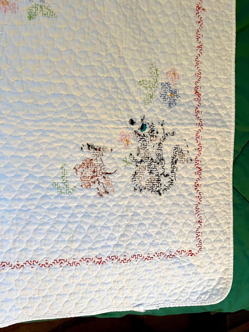 May include: White quilted blanket with embroidered floral and animal designs. The blanket features a red stitched border and diamond quilting pattern. The embroidered animals are brown and black, with colorful floral accents.