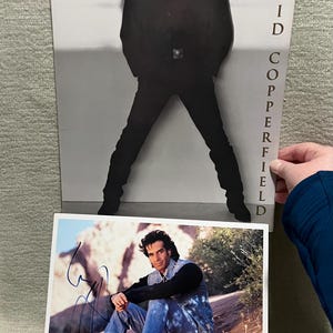 May include: Two photographs featuring David Copperfield. One is a black and white image of Copperfield in a black suit. The other is a color photo of Copperfield in a denim jacket and jeans, signed with a black marker.