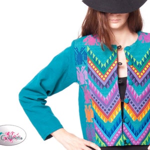 Peut inclure: Une veste bleu turquoise avec un motif brod&eacute; color&eacute; pr&eacute;sentant des motifs g&eacute;om&eacute;triques et des oiseaux. La veste a une fermeture &agrave; boutons.