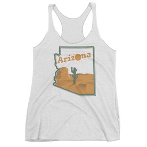 May include: A white tank top with a graphic of the state of Arizona. The graphic features a cactus, a sun, and the word "Arizona" in a vintage style font.