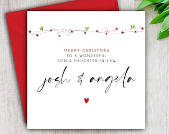 May include: A Christmas card with a red envelope. The white card has the text "MERRY CHRISTMAS TO A WONDERFUL SON & DAUGHTER-IN-LAW" in red. The names "Josh & Angela" are written in black script, with a red heart below.