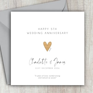 May include: A white wedding anniversary card with a gray envelope. The card reads "HAPPY 5TH WEDDING ANNIVERSARY" above a wooden heart. Below the heart are the names "Charlotte & James" and the date "31ST DECEMBER 2026".