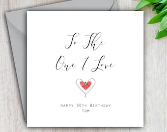 May include: A white card with black calligraphy that reads "To the One I Love" with a red heart and the text "Happy 30th Birthday Tom".