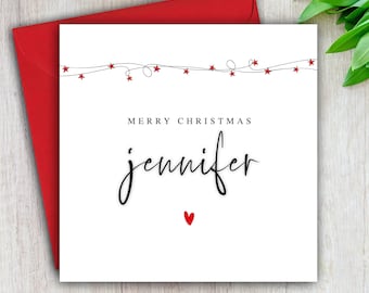May include: A white Christmas card with a red envelope. The card reads "Merry Christmas Jennifer" in black script, with a small red heart and red star accents.