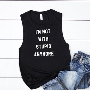 May include: Black sleeveless tank top with the text "I'M NOT WITH STUPID ANYMORE" in white.