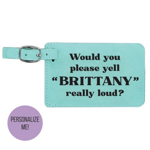 May include: A turquoise leather luggage tag with a black strap and the text "Would you please yell "BRITTANY" really loud?"