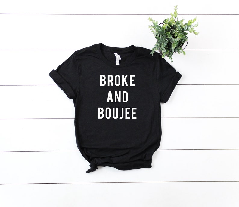 以下が含まれることがあります： 「Broke and Boujee」という白い文字が書かれた黒いTシャツ。