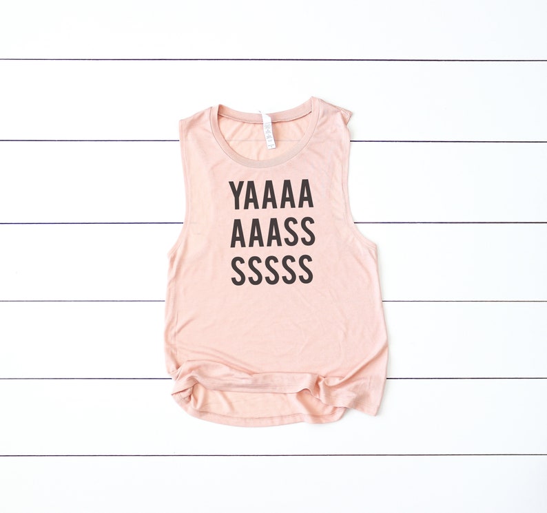 May include: A light pink sleeveless tank top with the text "YAAAA AAAAS SSSSSS" printed in black.