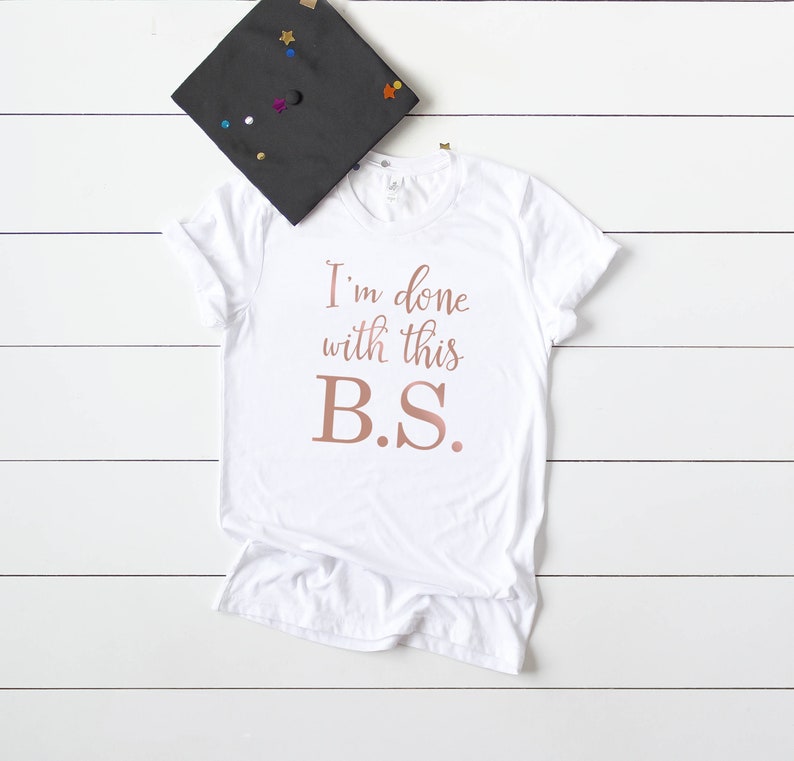 May include: White t-shirt with the text "I'm done with this B.S." in rose gold lettering.