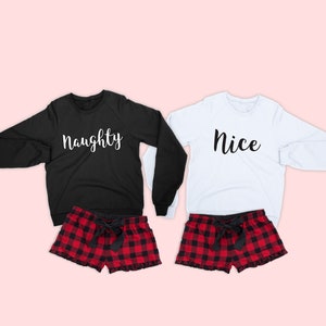 May include: Two matching sets of pajamas, one black and one white, with the words "naughty" and "nice" printed on the shirts. The bottoms are red and black plaid with a black bow.