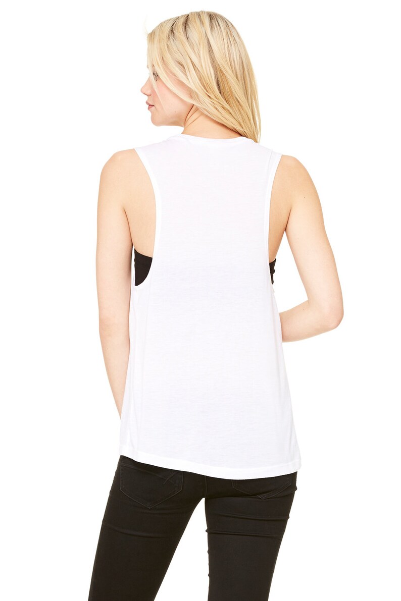 May include: White sleeveless muscle tank top with a relaxed fit. The tank top is made of a soft, comfortable fabric and has a slightly longer length.